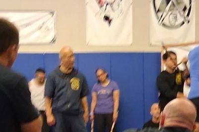Classroom with students sitting and standing on mat listening to Masters.